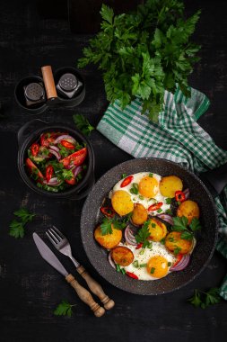 Kızarmış yumurta ve patates, soğanlı ve kırmızı biberli, köy usulü. Üst manzara, düz uzanma
