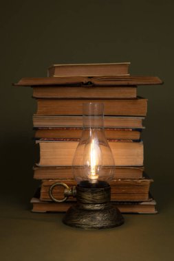 Eski kitaplar ve zeytin zemininde yanan bir lamba. Modern stilize lamba.