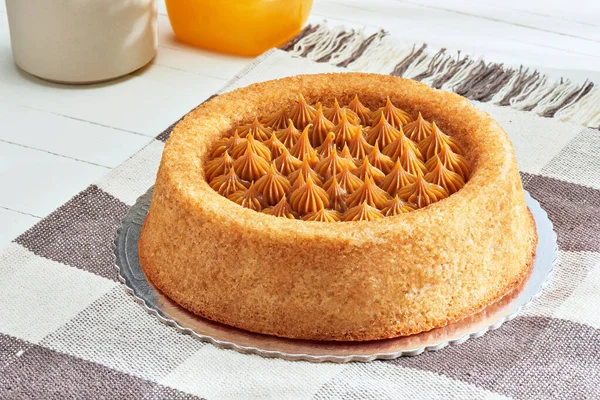 圆圆的香酥饼 配上糊糊和肉桂 巴西甜点 一个游泳池形状的自制蛋糕 放在石桌上 背景是餐巾纸和橙汁 — 图库照片