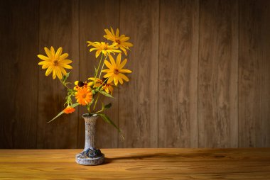 Durgun bir hayat, seramik bir vazoda çiçekler, ahşap bir masanın üzerindeki stüdyoda.