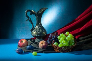 Hayat, metal sürahi, hasır sepetler ve ahşap bir masanın üzerinde stüdyoda çeşitli meyveler.