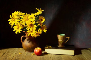 Hayat, seramik bir vazoda sarı çiçekler, elma, kitap ve çay fincanı ahşap bir masada.