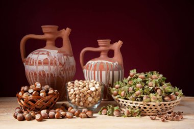 Hayat, iki seramik sürahi ve ahşap bir masada fındık.