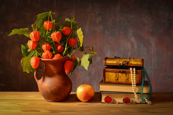 Still life, Alkekengi in a ceramic jug, apple and jewelry on the table