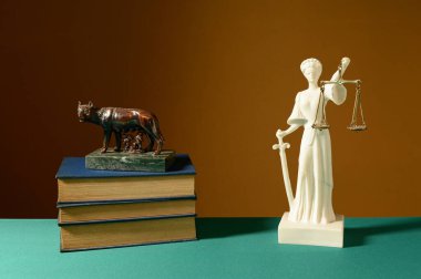 Hayat, kitaplar, dişi kurt figürü ve tahtadan bir masada Adalet Tanrıçası.