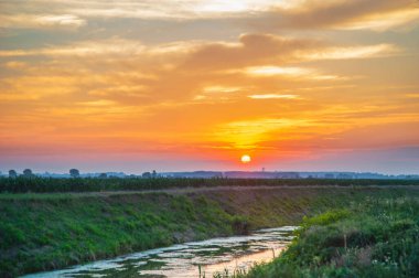 Sunrise by the canal with water near the village