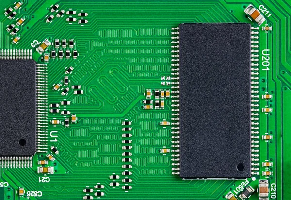 Semiconductor chips on electronic printed circuit board for high speed digital systems. Two microchips and small components as resistor or capacitor on green PCB from computer network hardware device.