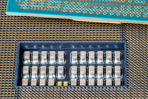 Electronic micro components in computer mainboard socket and a green processor detail. Closeup of small surface mounted devices on PCB inside slot for modern central processing unit. Microelectronics.