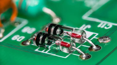 Yeşil baskılı devre kartında cam pakette iki nokta teması diyodu. Elektronik bileşenlerin germanyum kristali ve metal tel yarı iletken bağlantısıyla yakın plan PCB detayı üzerinde çizgili tüp. 