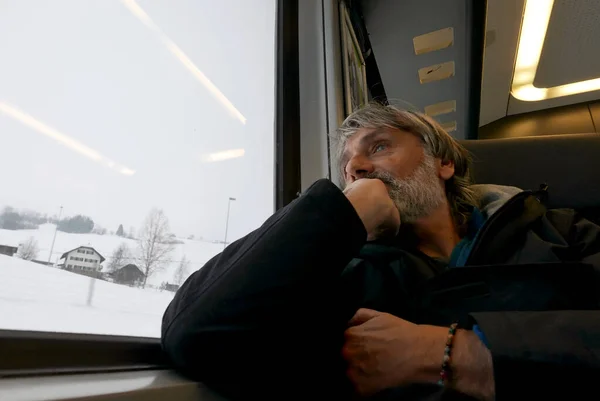 Pensiv Mogen Passagerare Tittar Genom Tågfönstret Snöigt Landskap Utanför — Stockfoto
