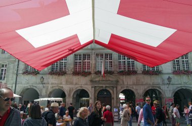LAUSANNE, SWitzERLAND - 5 AĞUSTOS 2023: İsviçre bayrağı altındaki insanlar tarihi belediye binasının önünde