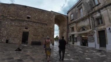 OTRANTO, İtalya - 6 Eylül 2024: Eski şehrin ana ortaçağ kapısından yürüyen insanlar
