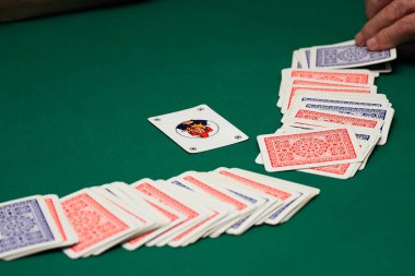 İskambil oynayıp kartları yeşil bir paspasın üzerinde kapalı tutarak.