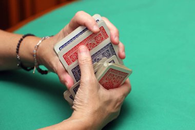 İskambil oynayıp kartları yeşil bir paspasın üzerinde kapalı tutarak.