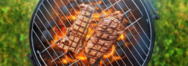 grilling steaks on charcoal bbq grill outdoors in yard shot from top view