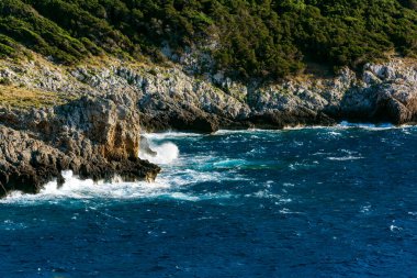 Deniz dalgalarının su sıçratarak kayalara çarpmasının güzel manzarası. Gialova, Moreloponnese, Yunanistan.