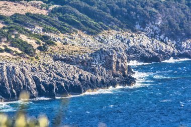 Deniz dalgalarının su sıçratarak kayalara çarpmasının güzel manzarası. Gialova, Moreloponnese, Yunanistan.