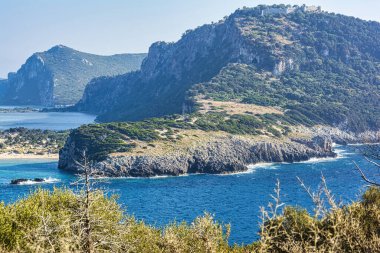 Açık gökyüzünün altında deniz ve dağlar var. Gialova Denizi, Mora, Yunanistan. Eski Navarino şatosunun uzak görüntüsü.