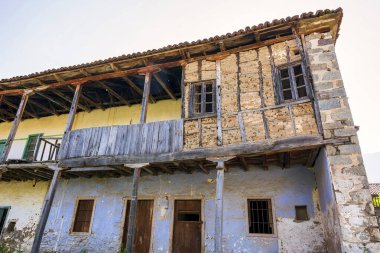 Elati, Trikala, Yunanistan 'da kırsal ve terk edilmiş geleneksel bir ev, yıpranmış ahşap balkonlar ve taş duvarlar sergileniyor, köyün tarihi cazibesini yansıtıyor..