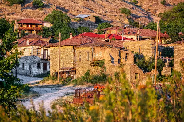 Yunanistan 'ın Agios Germanos kentindeki kırmızı kiremitli çatıları olan eski ve yıpranmış taş binaların manzarası köyün kırsal cazibesini ve geleneksel mimarisini yansıtıyor..