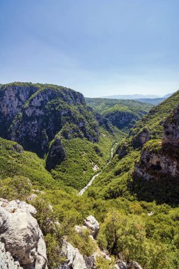 Yunanistan 'ın Zagori kentindeki Vikos Boğazı' nın muhteşem hava manzarası, açık bir gökyüzü altında sarp kayalıklar ve yemyeşil vadiler sergiliyor.