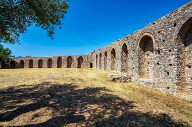 Yunanistan 'ın Messinia kentindeki Androusa Şatosu' nda açık bir gökyüzünün altında ortaçağ taş duvarları, kemerler ve zeytin ağaçları bulunuyor..