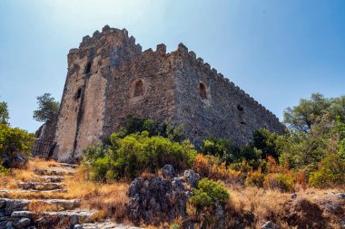 Yunanistan 'ın Messinia kentindeki Kapetanakis' in taş kulesi, manzaralı Akdeniz bitki örtüsü ve tepeleri arasında geleneksel Maniot mimarisini sergiliyor.