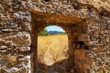 Kapetanakis Kulesi 'nin harabelerinde taş kemer, Messinia, Yunanistan, antik duvarları çerçevelemek ve manzaralı tarihi bir manzara.
