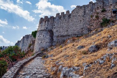 Yunanistan 'ın Mystras kentinden antik taş kale duvarları, ortaçağ mimarisi ve tepenin yamacında manzaralı bir kaldırım yolu sergiliyor..