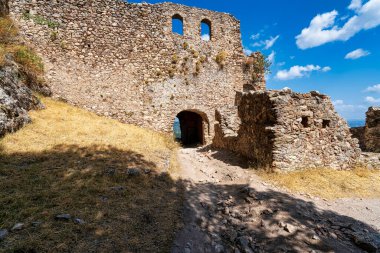 Yunanistan 'ın Mystras kentindeki antik taş kalıntıları ve güneşli bir kemer yolu, kurumuş ve engebeli bir manzaranın ortasındaki Bizans mimarisini vurguluyor.