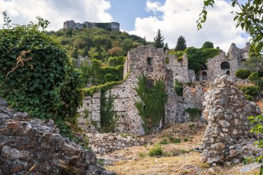 Yunanistan 'ın Mystras kentinde aşırı gelişmiş harabeler, sarmaşık kaplı taş duvarlar, antik mimari ve manzaralı bir tepe zemin.