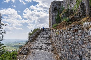 Yunanistan 'ın Mystras kentindeki kale duvarlarına uzanan taşla döşenmiş bir patika, etrafındaki vadinin panoramik manzarasını sunuyor..