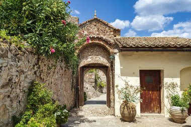 Mystras 'daki Pantanassa Manastırı' nın büyüleyici kemerli girişi çiçek açan çiçekler ve geleneksel taş duvarlarla çevrili..