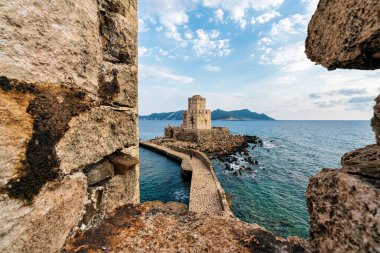 İyon Denizi ve kayalık kıyı şeridiyle çevrili taştan bir geçitle Methoni Kalesi 'ne bağlı ikonik Bourtzi Kulesi..