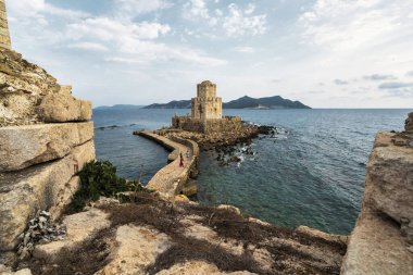 İyon Denizi ve kayalık kıyı şeridiyle çevrili taştan bir geçitle Methoni Kalesi 'ne bağlı ikonik Bourtzi Kulesi..