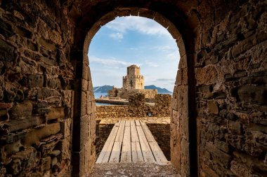 Methoni Kalesi 'ndeki sembolik Bourtzi Kulesi, tarihi yapıya doğru giden ahşap bir köprüyle taş bir kemer deliğinden görülüyor..