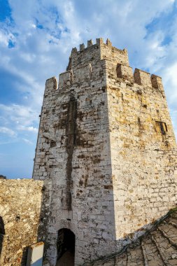 Methoni Kalesi 'ndeki yüksek bir taş kuleye yakın çekim, ortaçağ Venedik mimarisini ve öğleden sonra güneşinin altında yıpranmış duvarlarını vurguluyor..