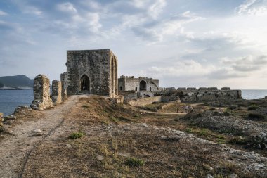 Methoni, Yunanistan - 25 Ağustos 2024: Methoni Kalesi 'ndeki antik kemerli salonun ve savunma duvarlarının manzarası, Venedik mimarisi ve kıyı çevresini vurguluyor.