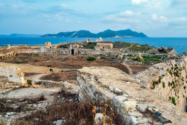 Methoni Kalesi 'nin genişleyen antik harabeleri, taş duvarlar ve İyon Denizi' ne karşı kurulmuş sahil zemininin manzarası..