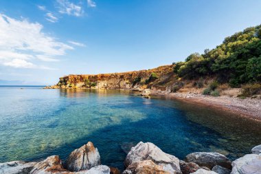 Koroni 'de sakin Akdeniz suları, dağınık kayalar ve bulutlu bir gökyüzünün altında sakin bir ufuk..