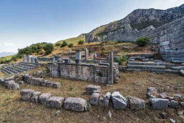 Yunanistan 'ın Messene kenti yakınlarındaki antik Arkadya Geçidi harabelerinde taş duvarlar, basamaklar ve berrak gökyüzü altında engebeli bir tepe manzarası yer alıyor..