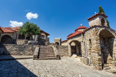 Yunanistan 'ın Mora kentinde, kırmızı kiremitli çatılar, kemerler ve mavi gökyüzünün altında sakin bir dağ zeminine sahip güzel bir taş manastır..