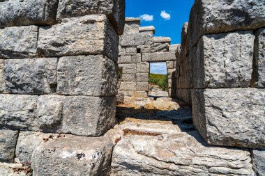 Yunanistan 'ın Messene kentinin antik duvarlarının taş kalıntıları, yemyeşil ve açık bir gökyüzünün altında yuvarlanan tepelerle çevrili..