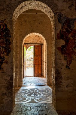 Yunanistan 'ın Messinia kentindeki Andromonastiro Manastırı' nda güneşli bir avluya açılan açık ahşap kapılı tarihi bir kemer..