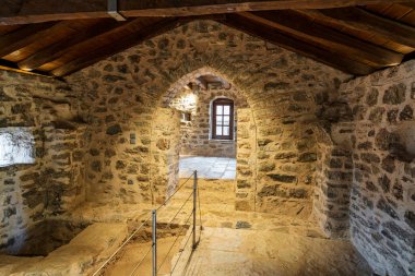Yunanistan 'ın Messinia kentindeki Andromonastiro Manastırı içinde ahşap tavan, küçük pencereler ve geleneksel duvarcılık içeren tarihi bir taş oda..