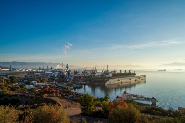 Yunanistan 'ın Elefsina kentindeki yoğun bir tersanede sabah gökyüzünün altında vinçler, rıhtım gemileri ve sanayi binaları bulunuyor..