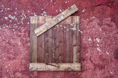 Yunanistan 'ın Lavreotiki kentindeki tarihi gümüş madenlerindeki eski madencilerin evlerinden kalma kırmızı lekeli bir duvarın üzerinde yıpranmış ahşap bir pencere kepengi..