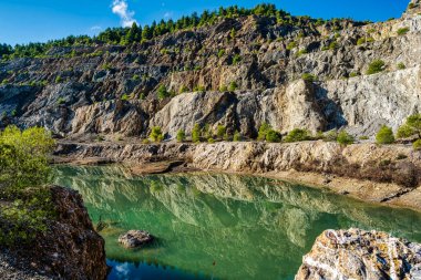 Yunanistan 'ın Evia kentindeki terk edilmiş bir taş ocağında bulunan yapay göl engebeli uçurumları, seyrek bitki örtüsünü ve sakin, yeşil bir su yüzeyini yansıtıyor..