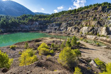 Yunanistan 'ın Evia kentindeki terk edilmiş bir taş ocağında bulunan yapay göl engebeli uçurumları, seyrek bitki örtüsünü ve sakin, yeşil bir su yüzeyini yansıtıyor..