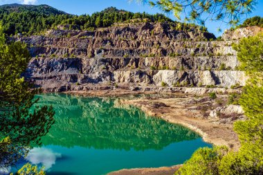 Yunanistan 'ın Evia kentindeki terk edilmiş bir taş ocağında bulunan yapay göl engebeli uçurumları, seyrek bitki örtüsünü ve sakin, yeşil bir su yüzeyini yansıtıyor..